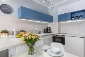 a kitchen with blue cabinets and a vase of flowers on a table at Apartment Leśne Tarasy Dziwnówek by Noclegi Renters in Dziwnówek
