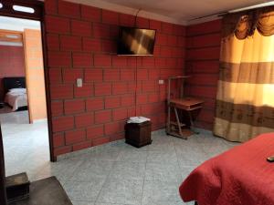 a bedroom with a red brick wall with a television at Casa Hotel Los Faroles- Samaná/Caldas in Samaná