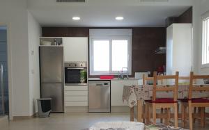 a kitchen with a table and a refrigerator and a table and chairs at VILLA DE SUABIA, Casa 9 in San Fulgencio