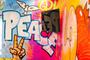 a wall covered in graffiti with a peace sign at Art Deco Graffiti Suite in Philadelphia
