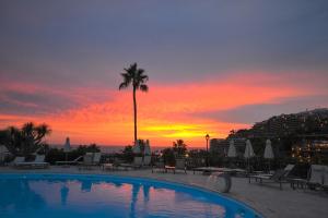 a pool with a palm tree and a sunset at Apartamento en Aquamarina in Mogán +4 photos