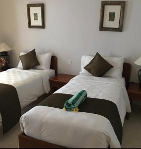 2 Betten in einem Hotelzimmer mit grüner Decke in der Unterkunft Peninsula Beach Resort in Nusa Dua