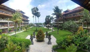 une cour d'un immeuble d'appartements avec des arbres et des buissons dans l'établissement Peninsula Beach Resort, à Nusa Dua
