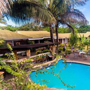 a resort with a swimming pool and palm trees at CHEZ MARIA GORETTI HOTEL in Hanga Roa