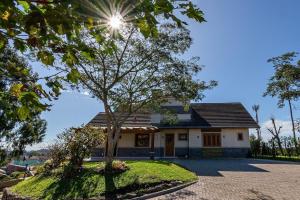 una casa con un árbol delante en Rosa Casa Vivendas da Colina, en Canela