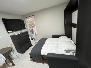 a bedroom with a bed and a flat screen tv at Le Centre-Ville in Rouyn-Noranda