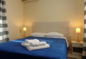 - une chambre avec un lit bleu et des serviettes dans l'établissement Porto View Suites and Apartments, à Porto Heli