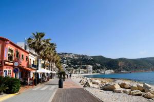 une plage avec des bâtiments, des palmiers et l'eau dans l'établissement Wind Rose study, à Jávea