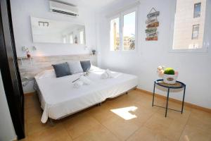 a bedroom with a white bed and a table at Wind Rose Study Xàbia in Jávea
