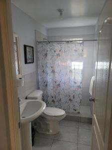 a bathroom with a toilet and a sink and a shower curtain at Debra's Place Lot 147 in Priory