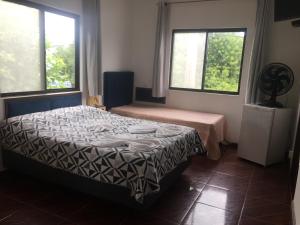 a bedroom with a bed and two windows at Pousada La Marea in Rio Grande