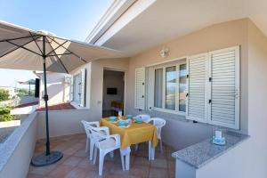 eine Terrasse mit einem gelben Tisch, Stühlen und einem Sonnenschirm in der Unterkunft Casa Salvo in Budoni