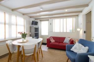 een woonkamer met een tafel en een rode bank bij Strand & Meer Domburg in Domburg