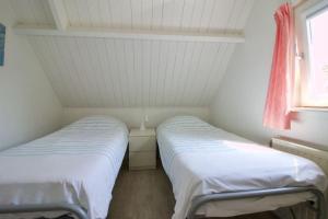 twee bedden in een kleine kamer met een raam bij Strand & Meer Domburg in Domburg