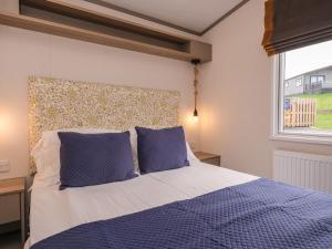 a bedroom with a bed with blue pillows and a window at St Mawgan's Cove 1 in Newquay