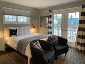 a bedroom with a large bed and two chairs at Acadia Hotel - Downtown in Bar Harbor
