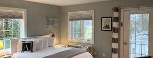 a bedroom with a bed with white pillows and windows at Acadia Hotel - Downtown in Bar Harbor