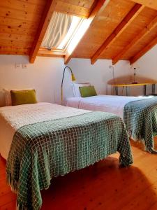 two beds in a room with wooden ceilings at Naturarte Rio - Duna Parque Group in Vila Nova de Milfontes