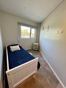 a small room with a bed with a blue blanket at Frente a la playa, encantador departamento en PB in Puerto Madryn +8 photos
