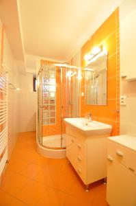 ein orangefarbenes Badezimmer mit einer Dusche und einem Waschbecken in der Unterkunft Rodinný dom "Ako doma" in Veľký Slavkov