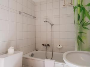 a white bathroom with a tub and a sink at Apartment Christiania 2 C8 by Interhome in Nendaz