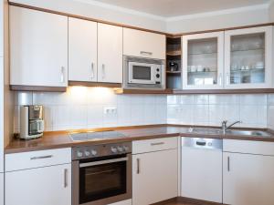a kitchen with white cabinets and a microwave at Apartment Seepark Sellin-4 by Interhome in Ostseebad Sellin
