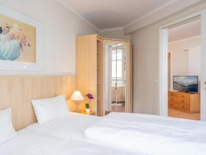 a bedroom with a large white bed and a television at Apartment Seepark Sellin-4 by Interhome in Ostseebad Sellin +18 photos