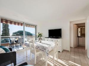 a white dining room with a table and a television at Apartment Les Jardins del Mar-2 by Interhome in Cavalaire-sur-Mer