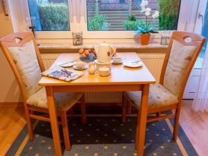 ein Holztisch mit Stühlen und ein Teller mit Essen drauf in der Unterkunft Apartment Am Nordkap-2 by Interhome in Norddeich