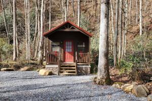 a small cabin with a red door in the woods at Sweet Pea Tiny Home in Bryson City