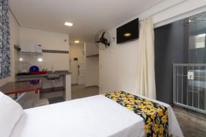 a bedroom with a white bed and a kitchen at Apto Bela Vista São Paulo in Sao Paulo