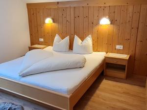 Schlafzimmer mit einem Bett mit weißer Bettwäsche und Kissen in der Unterkunft Apartment Walch - PTZ410 by Interhome in Fendels