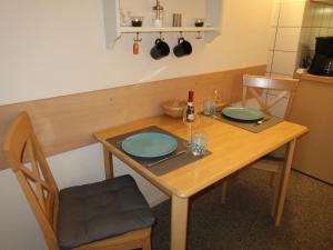 a wooden table with two plates and a bottle of wine at Apartment Tossens-8 by Interhome in Butjadingen OT Tossens