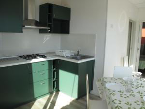 een keuken met groene kasten en een tafel met een stoel bij Holiday Home Gelsomino - SLR403 by Interhome in San Lorenzo al Mare