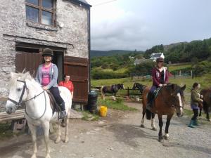 two women riding horses in front of a building at The Ferry Boat in Portmagee