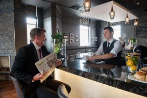 deux hommes debout à un comptoir dans un bar dans l'établissement The Halston Carlisle, à Carlisle
