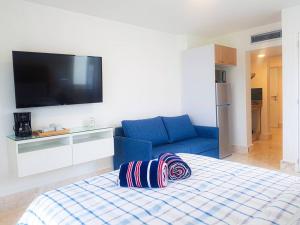 Apartamento en Playa Dorada, Green One في سان فيليبي دي بويرتو بلاتا: غرفة نوم بسرير ازرق واريكة زرقاء