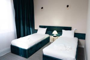 duas camas num quarto de hotel com lençóis brancos em Jardin em Aqtöbe