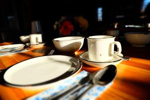 una mesa de madera con platos blancos, tazas y cucharas en schmiede1860, en Groß Dratow