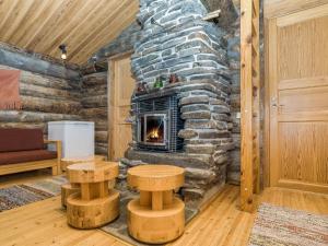 a log cabin living room with a stone fireplace at Holiday Home Kuontijärvi a by Interhome in Ruka