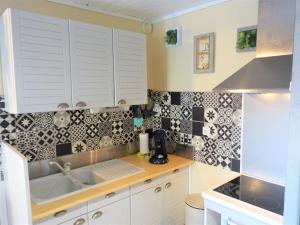una cocina con armarios blancos y azulejos blancos y negros en Holiday Home Les Balcons de la Méditerranée-26 by Interhome en Narbonne-Plage