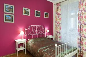 a bedroom with pink walls and a bed with two tables at Apartamenty Gołębia 3 in Krakow