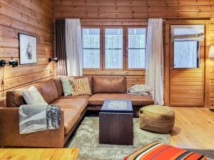 ein Wohnzimmer mit einem braunen Sofa und einem Tisch in der Unterkunft Holiday Home Purnukka by Interhome in Ruka