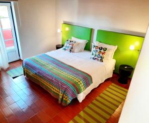 a bedroom with a large bed with colorful sheets and pillows at Naturarte Rio - Duna Parque Group in Vila Nova de Milfontes