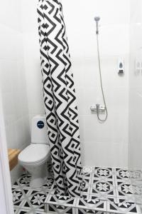 a bathroom with a toilet and a black and white shower curtain at Jardin in Aktobe