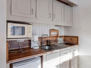 a kitchen with white cabinets and a sink and a microwave at Studio La Christaz-7 by Interhome in Saint-Gervais-les-Bains