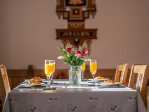 a table with a vase of flowers and glasses of orange juice at Holiday Home Ceilidhtail Cottage by Interhome in Drumnadrochit