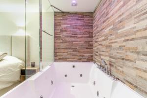 La salle de bains est pourvue d'une baignoire et d'un mur en briques. dans l'établissement Studio Stand by Me, à Villeneuve-le-Roi