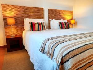 una camera d'albergo con un grande letto con due cuscini di Naturarte Rio - Duna Parque Group a Vila Nova de Milfontes