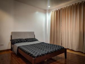 1 dormitorio con 1 cama y una ventana con cortinas en Beautiful 3br townhouse with garden and bonfire, en Baguio